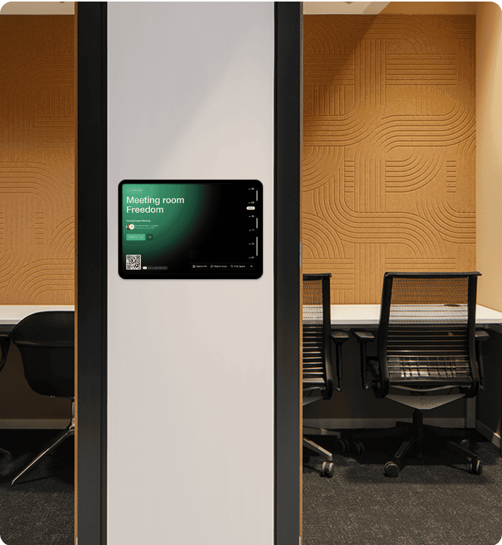A tablet mounted outside a meeting room named "Freedom," displaying booking details and a QR code for check-in.